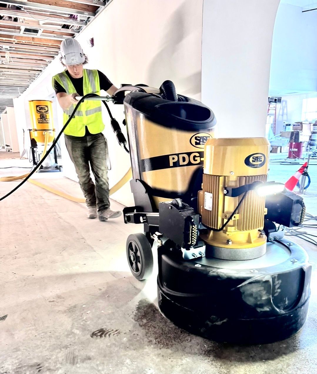 Worker operating a floor polisher in a bright indoor construction area