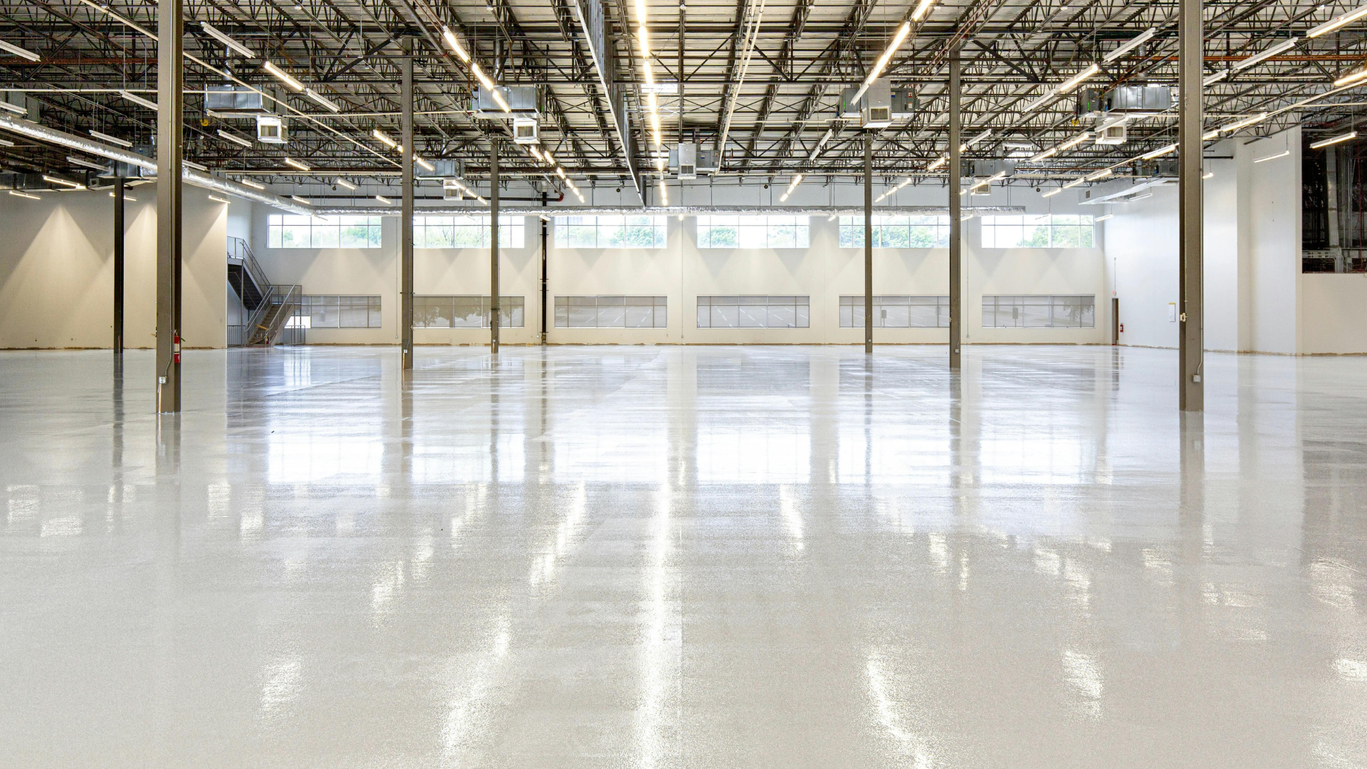 Empty industrial warehouse with polished concrete floor and exposed ceiling beams