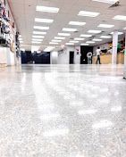 Bright indoor hallway with a glossy floor, ceiling lights, and a few people in the distance