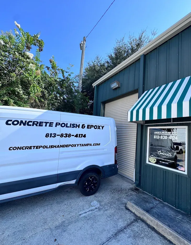 White service van parked beside a green building with a striped awning and a concrete polishing business sign.