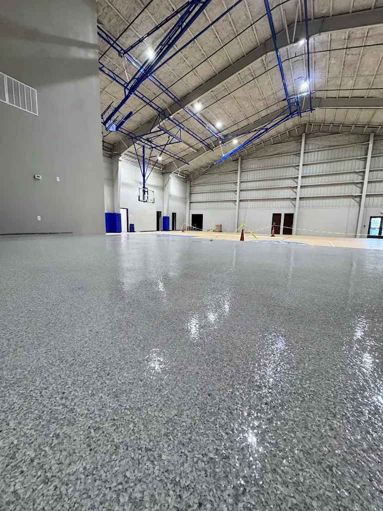 Empty indoor warehouse with a polished speckled floor and high arched ceiling
