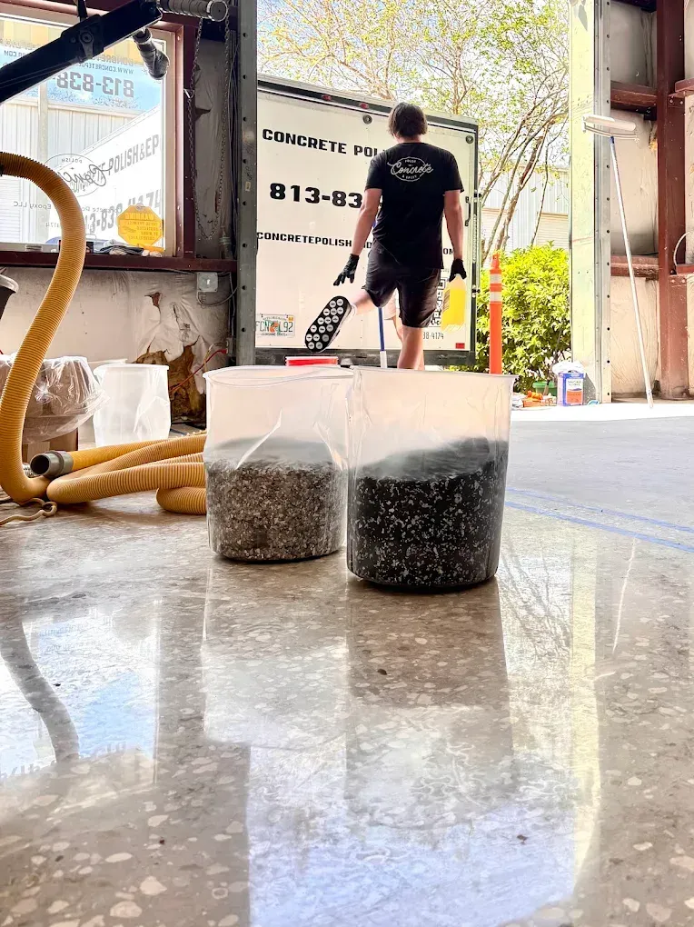 Two clear containers of gravel on a shiny floor, with a person walking in the background.