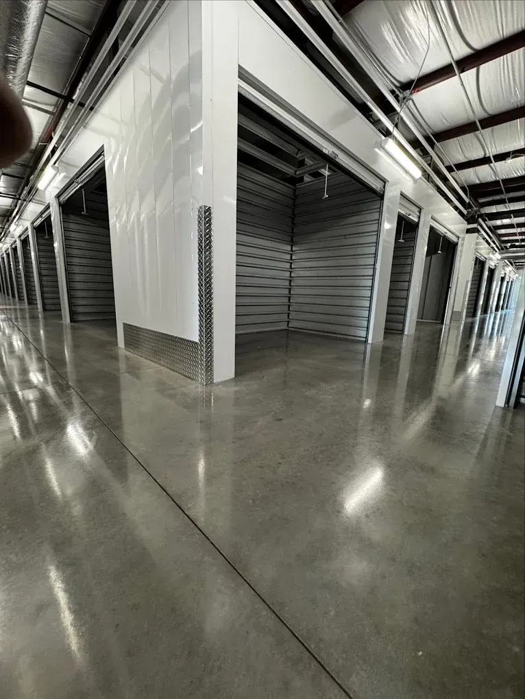 Empty industrial corridor with metal roll-up doors and polished concrete floor
