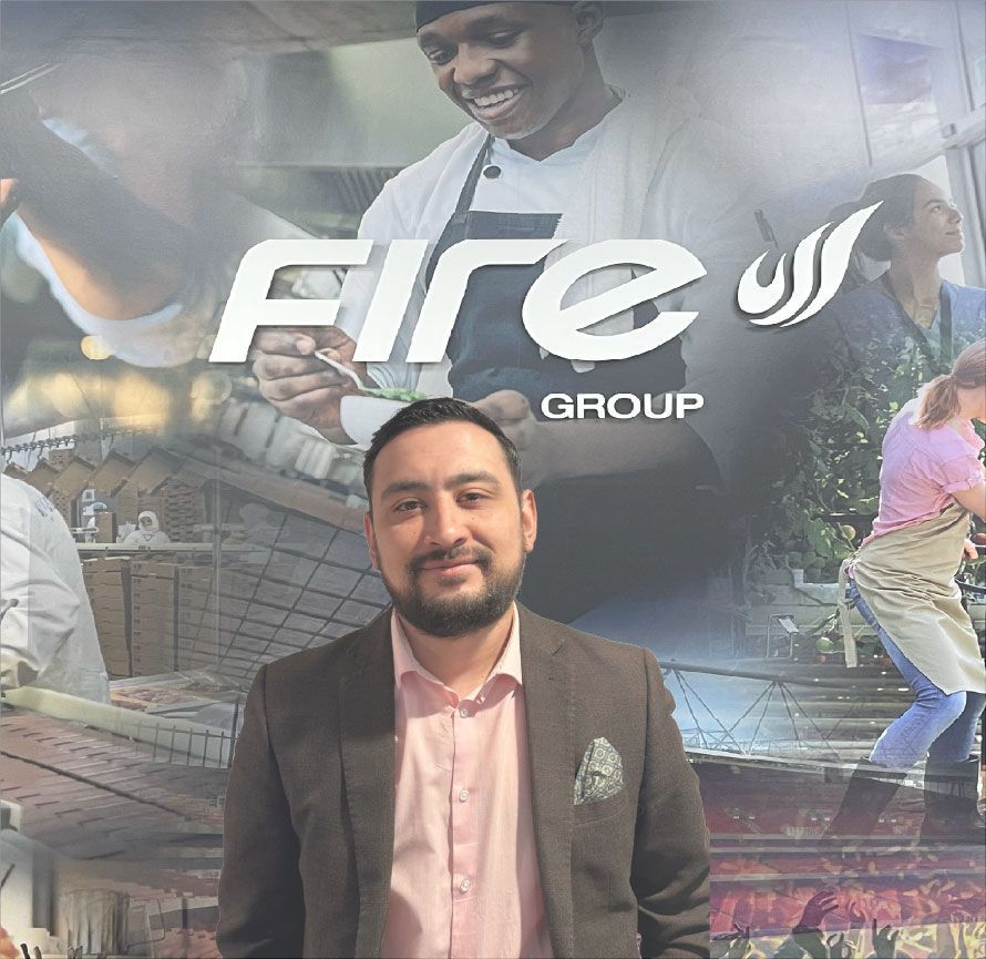 Man in a suit smiles in front of a Fire Group graphic featuring culinary scenes.
