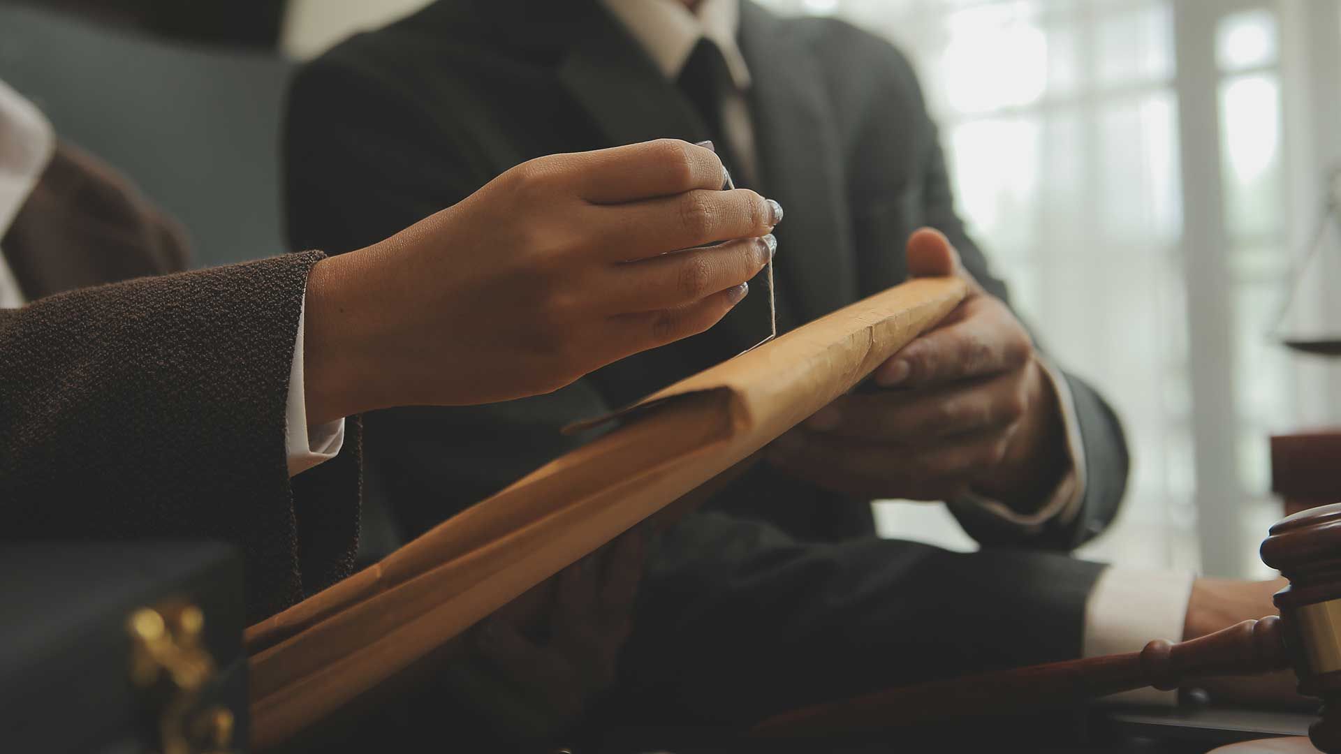 A man and a woman are sitting at a table holding a folder.
