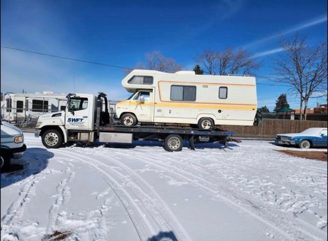 A rv is being towed by a tow truck in the snow.