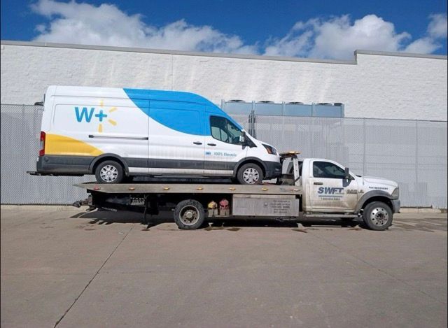 A walmart van is sitting on top of a tow truck.