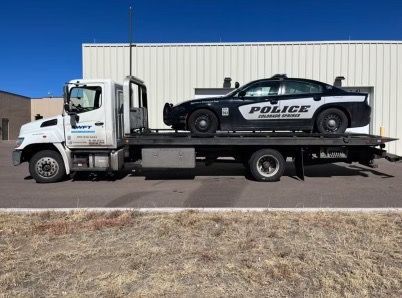 A police car is sitting on top of a tow truck.