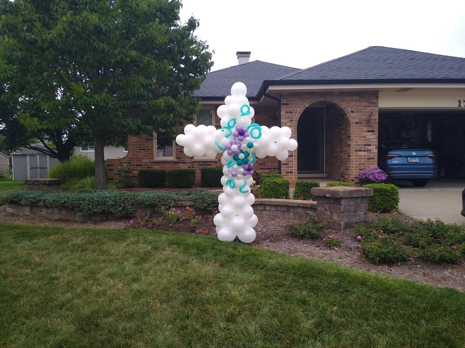 Pastel balloon display in front of a suburban house and driveway