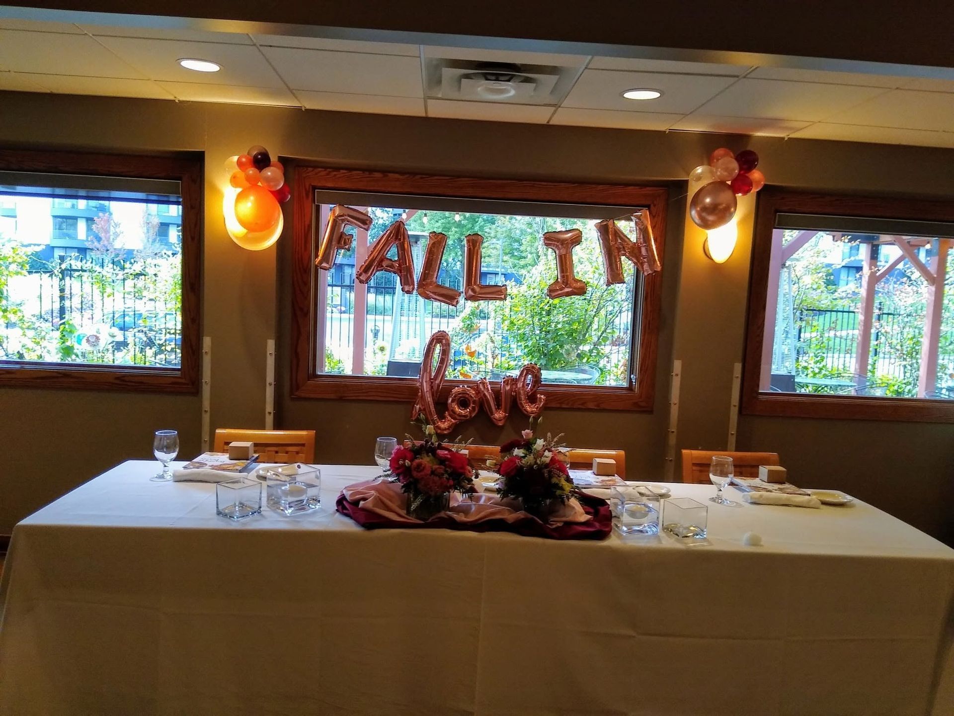 Decorated banquet table with candles and flowers in front of windows spelling “ALL IN”