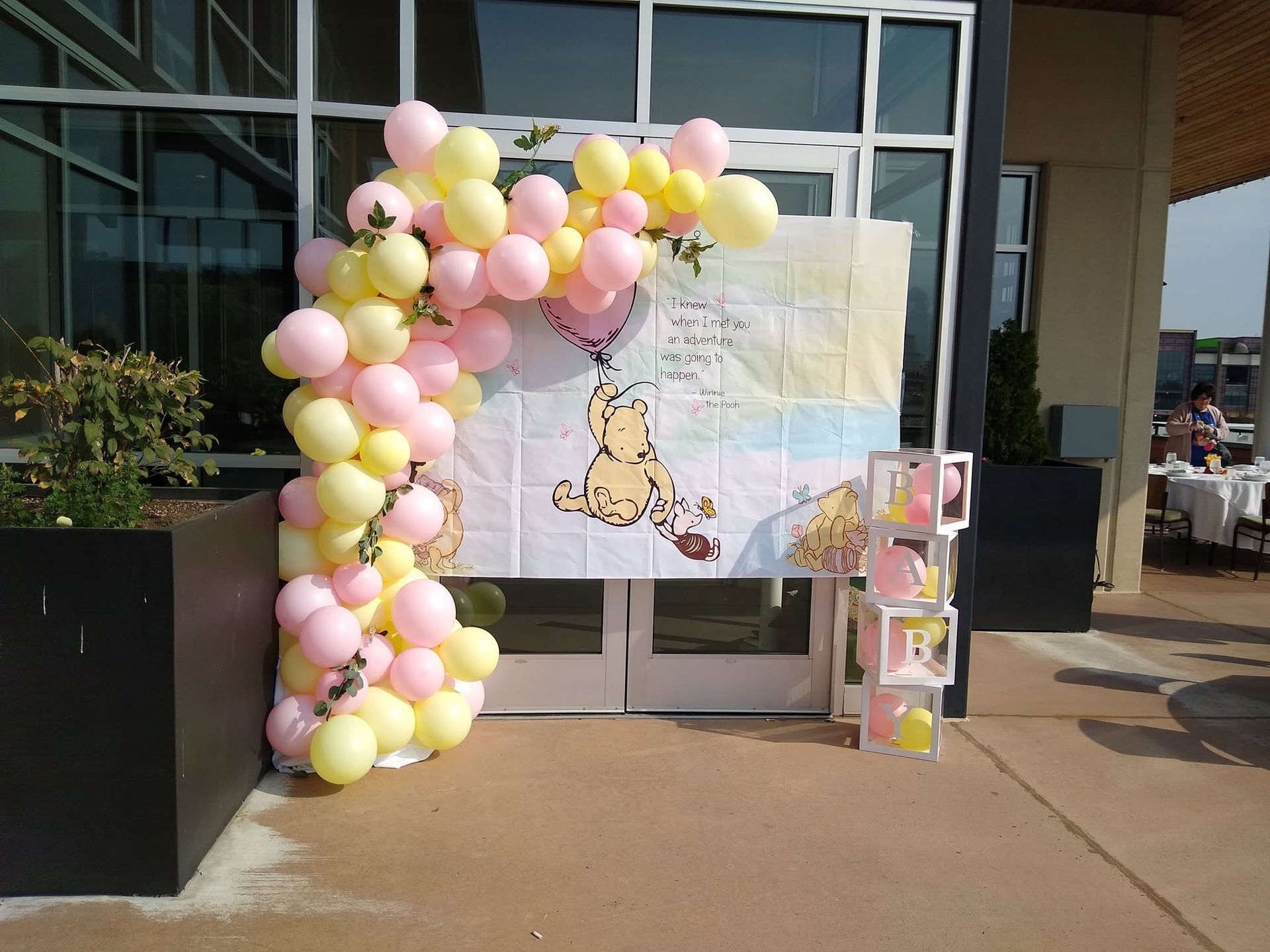 Pastel balloon arch framing a decorated poster board outside a glass doorway