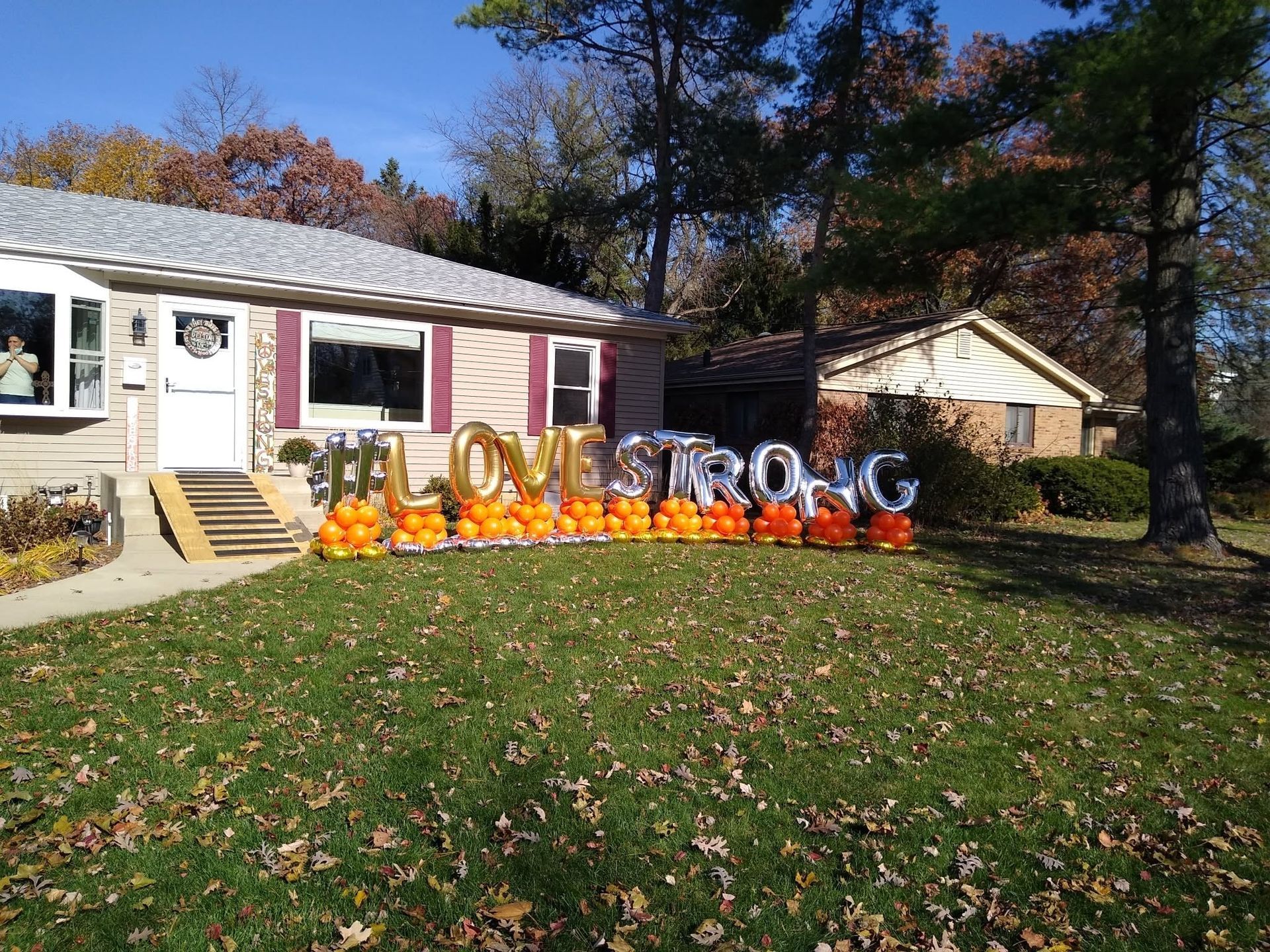 Halloween decorations with lit letters and pumpkins on a lawn in front of a house