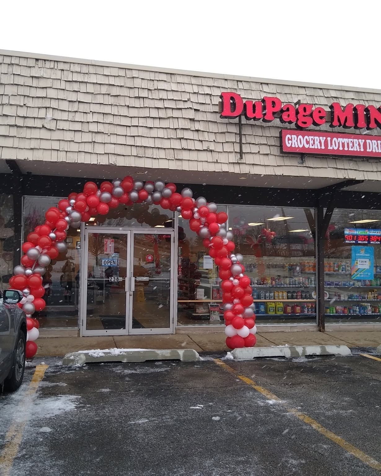 DuPage Mint storefront with a red-and-white balloon arch over the entrance on a snowy day