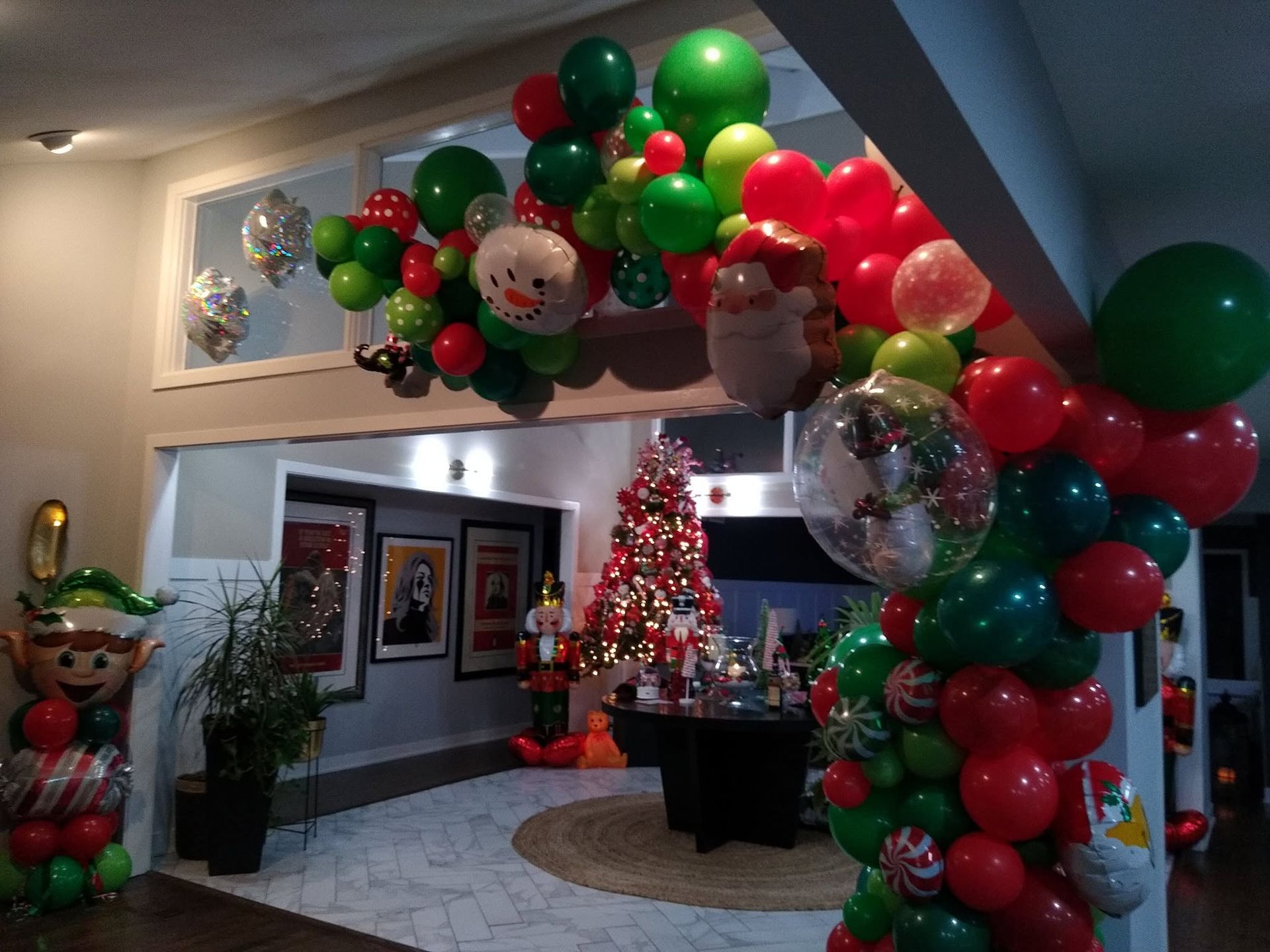 Holiday lobby decorated with red, green, and silver balloons and a lit Christmas tree