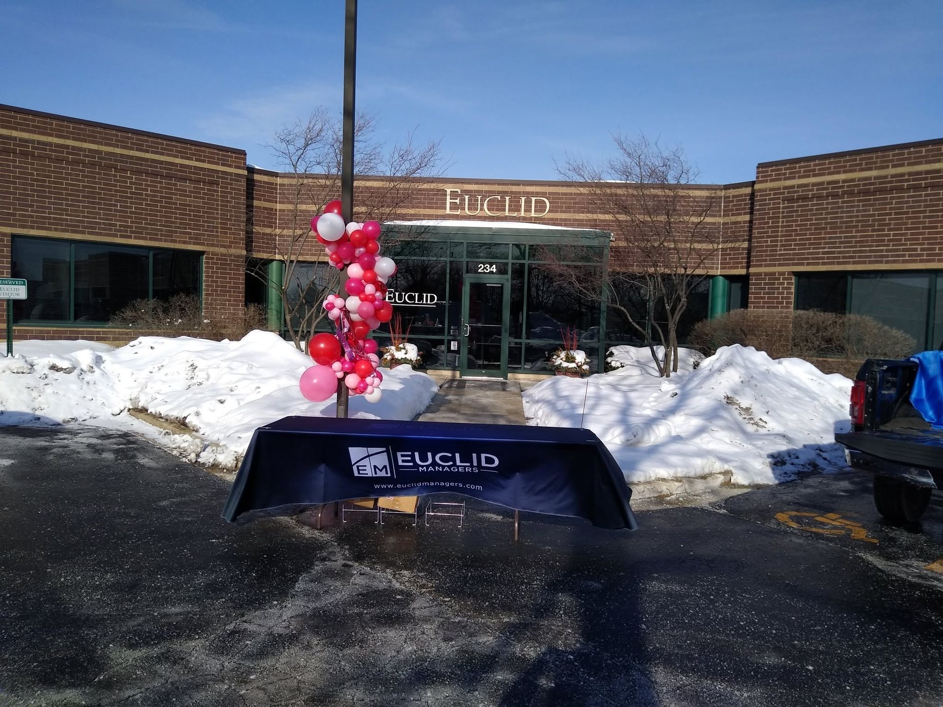 Euclid school entrance with snow, a red balloon display, and a table outside