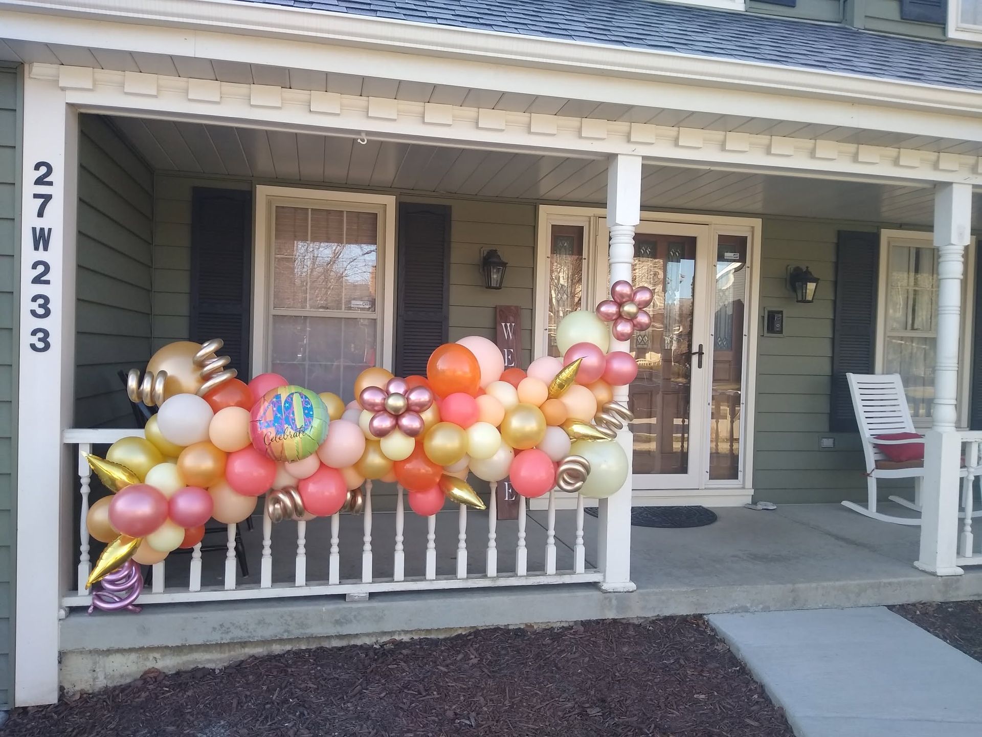 Porch decorated with a colorful balloon garland in front of a house