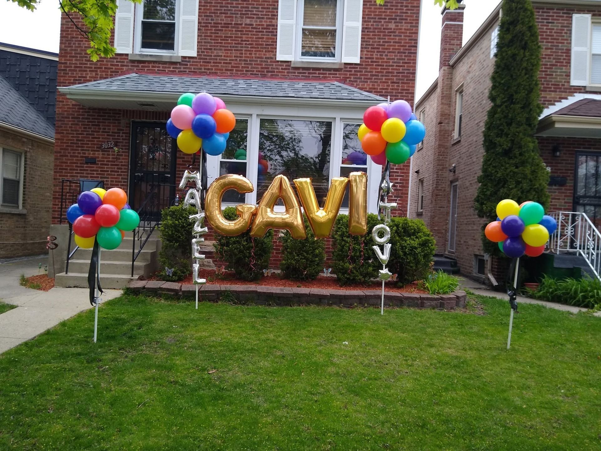 Backyard birthday setup with gold “GAVI” balloons and colorful balloon bouquets on a lawn