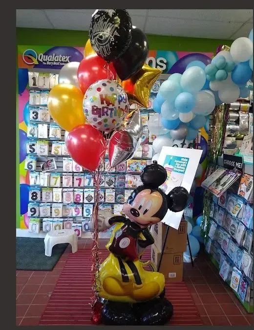 Mickey Mouse birthday balloon display in a store aisle with colorful balloons and cards