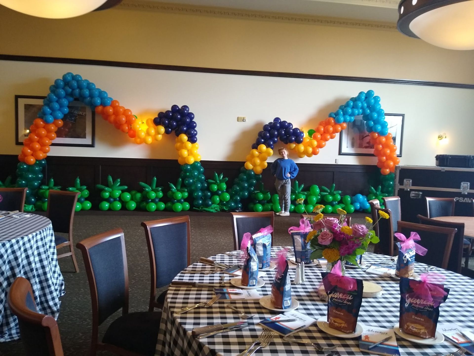 Balloon arches and floral centerpieces decorating a banquet hall with checkered tablecloths