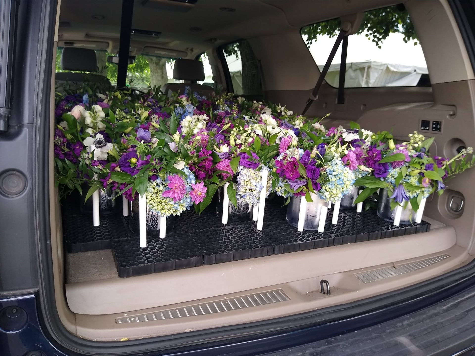 Van loaded with rows of purple, white, and green floral bouquets in the cargo area