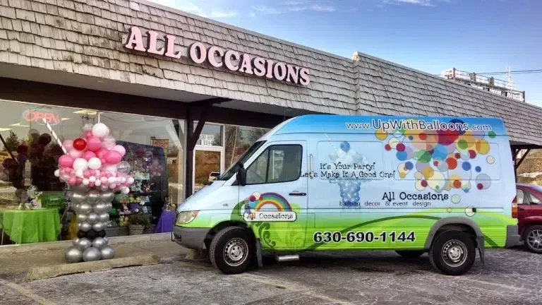 White-and-green A&E Occasions van parked outside a shop decorated with pink and silver balloons