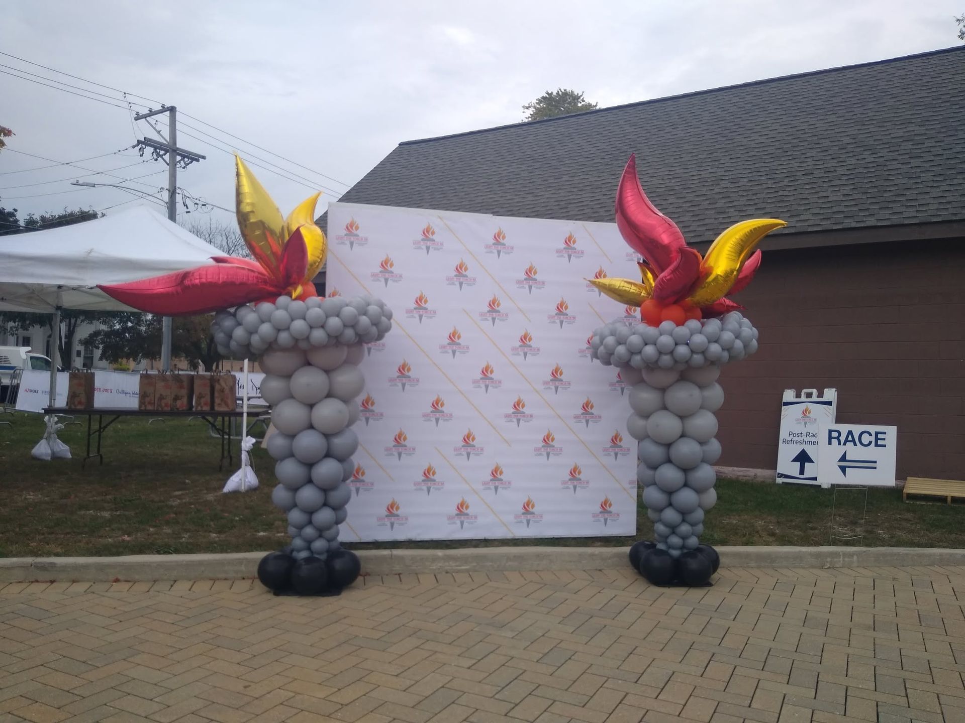 Outdoor event archway with balloon columns and red-yellow bird decorations in front of a backdrop.