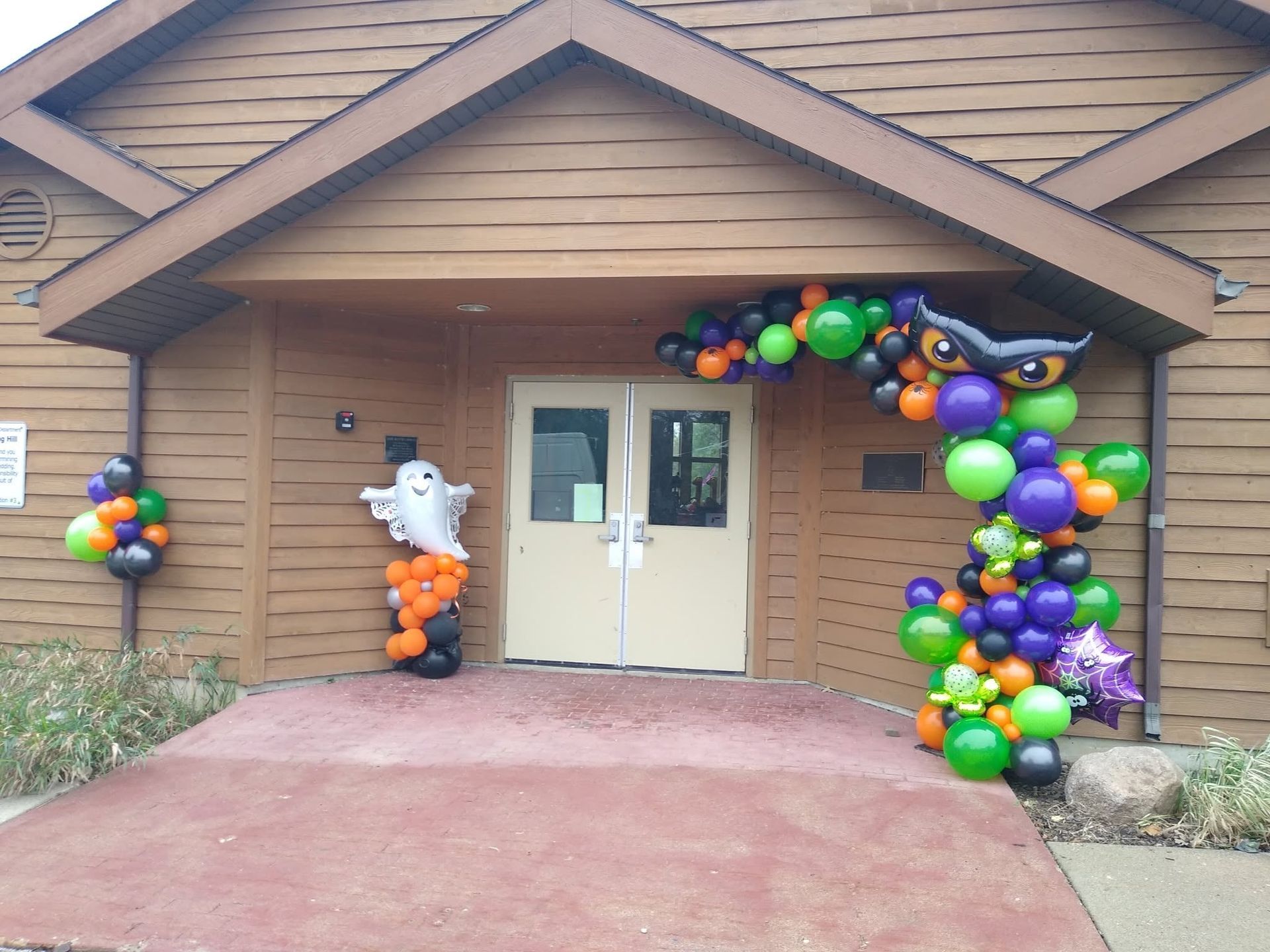 House entrance decorated with colorful balloons and Halloween figures on the porch