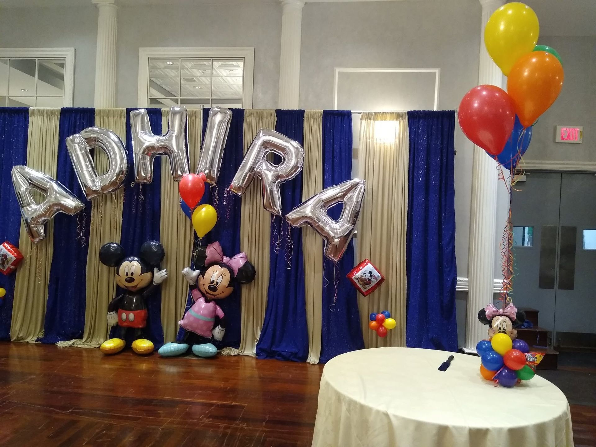 Mickey and Minnie balloon display with silver letters and colorful balloons on a decorated stage
