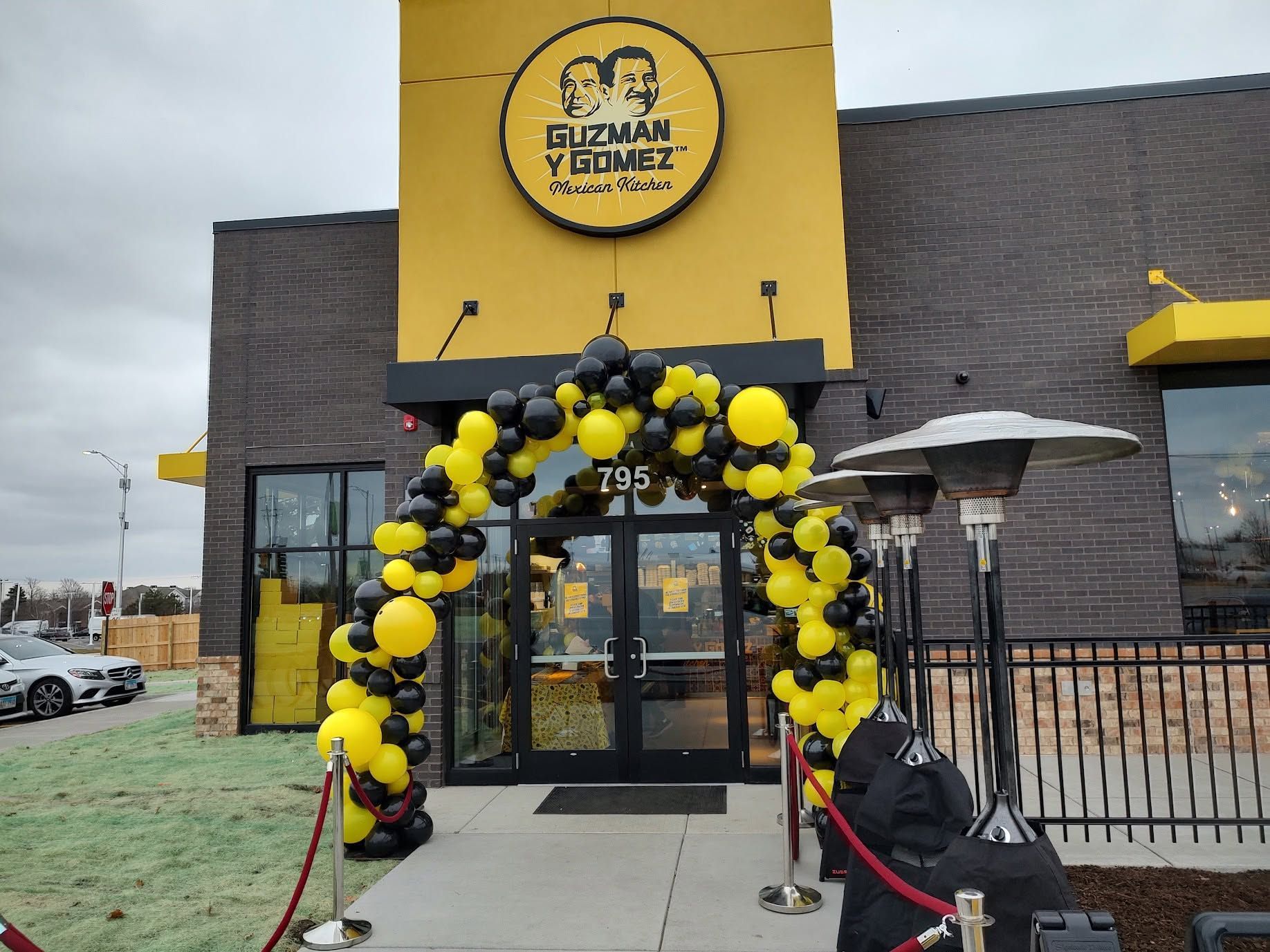 Yellow-and-black balloon arch at entrance of Suzy’s Tummy in a brick building