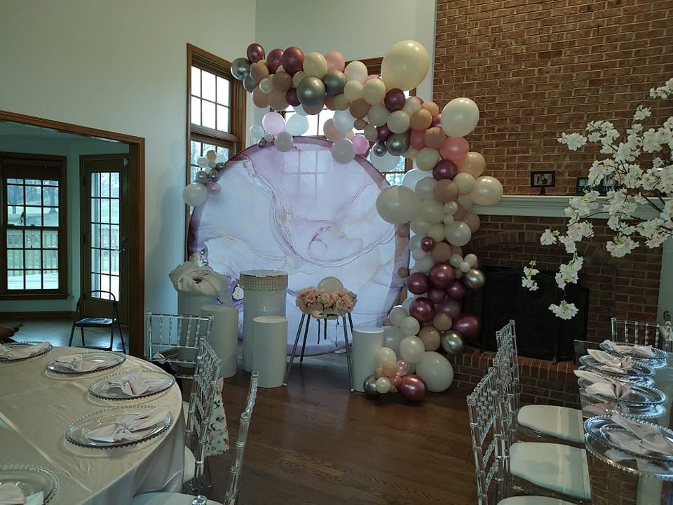 Balloon arch around a pastel backdrop at an elegant indoor event setup