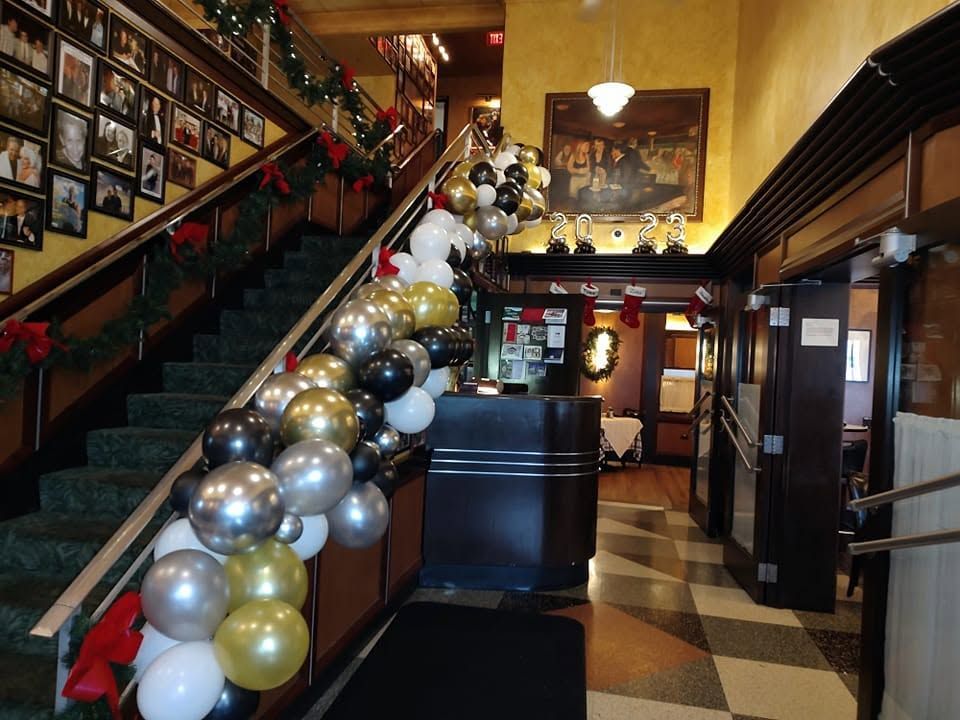 Decorated lobby with a staircase wrapped in balloons and framed photos on the walls