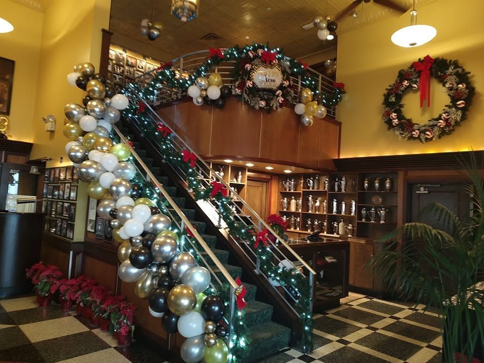 Decorated indoor staircase with Christmas garlands, ornaments, and a wreath in a warmly lit lobby