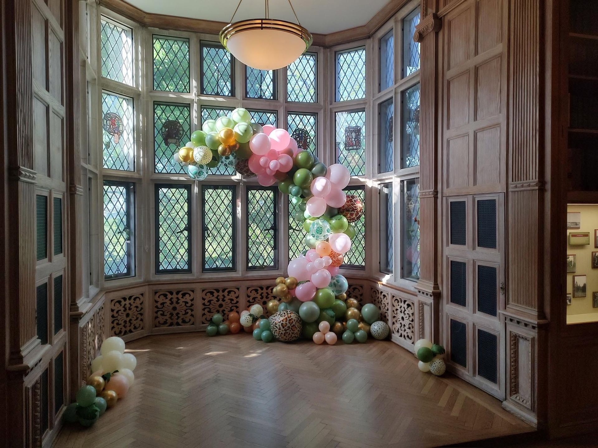 Elegant room with tall windows and pastel balloon decorations on the floor and near the corner.