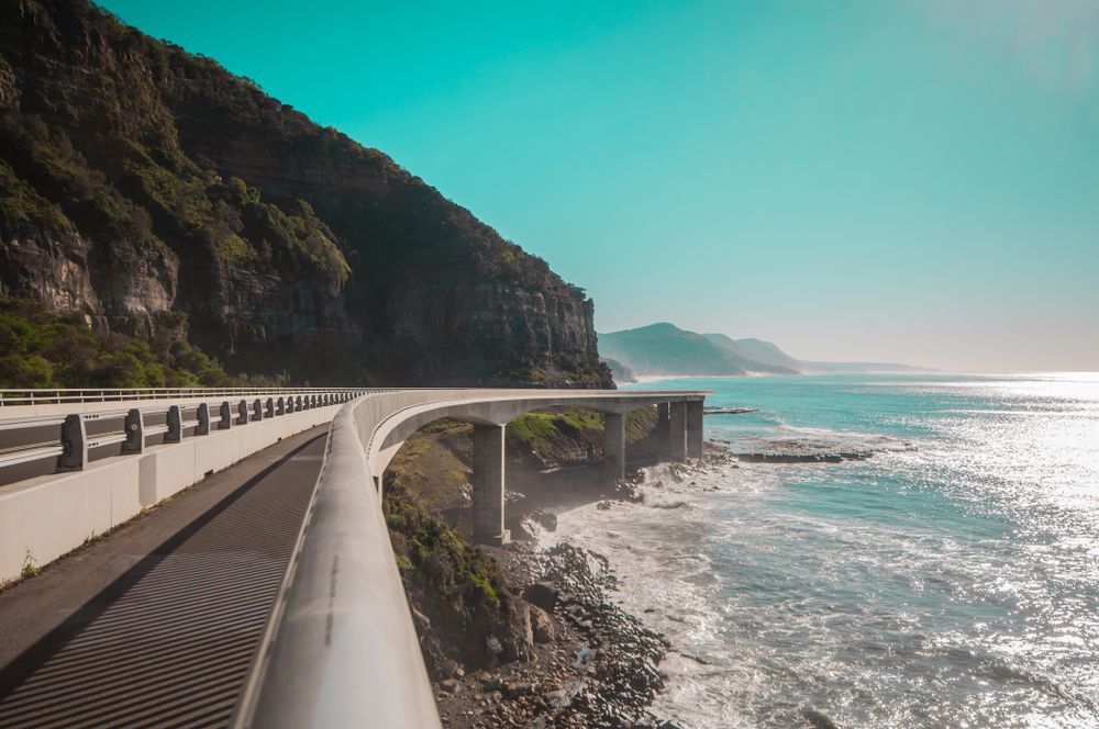 A Coastal Road Curves Along a Cliffside — Dave's Drive U Anywhere 24/7 Mini Van Hire In Kiama, NSW