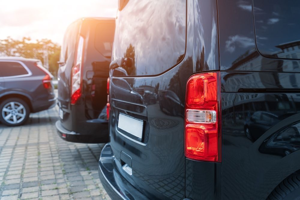 Black Vans Parked on a Paved Lot With Sunlight — Dave's Drive U Anywhere 24/7 Mini Van Hire In Kiama, NSW