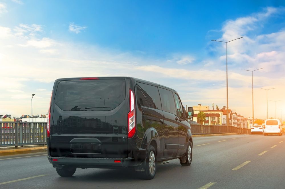 Black Van Driving on a Road Under a Blue Sky — Dave's Drive U Anywhere 24/7 Mini Van Hire In Kiama, NSW