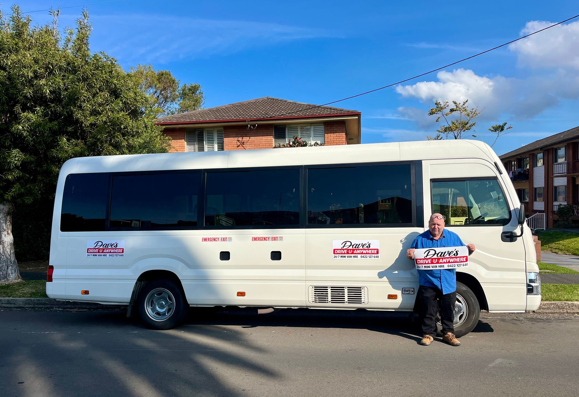 Man With Boxes Stands Next to a White Bus — Dave's Drive U Anywhere 24/7 Mini Van Hire In Wollongong, NSW