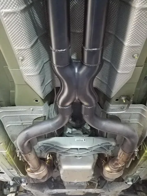 A close up of the underside of a car with exhaust pipes | Ed Hanson's Muffler Service