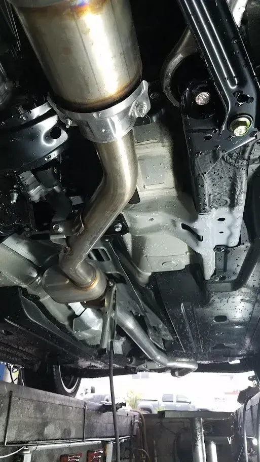 A close up of the underside of a car with exhaust pipes | Ed Hanson's Muffler Service