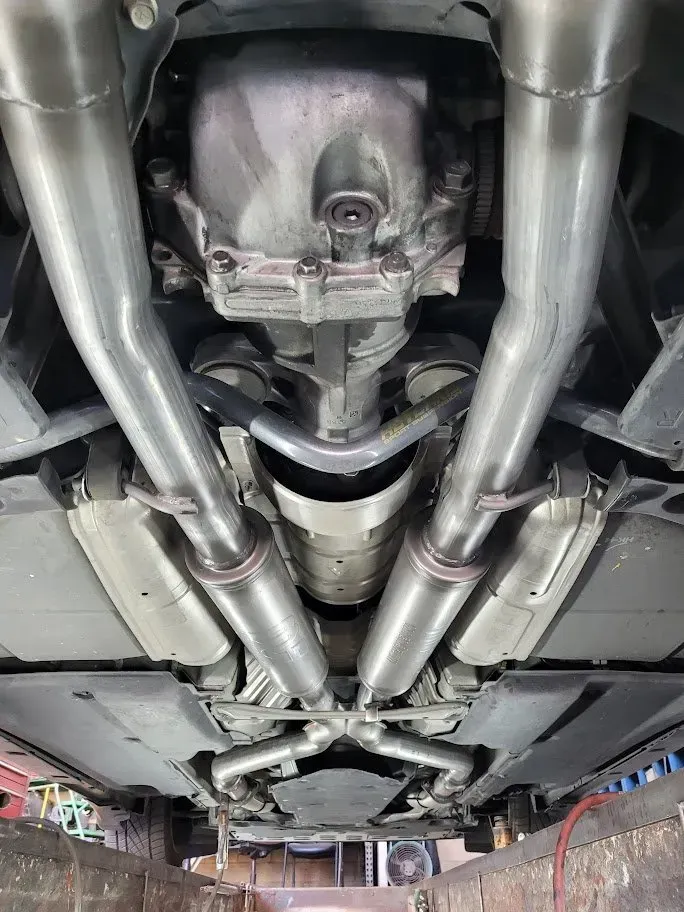 A close up of the underside of a car with exhaust pipes | Ed Hanson's Muffler Service