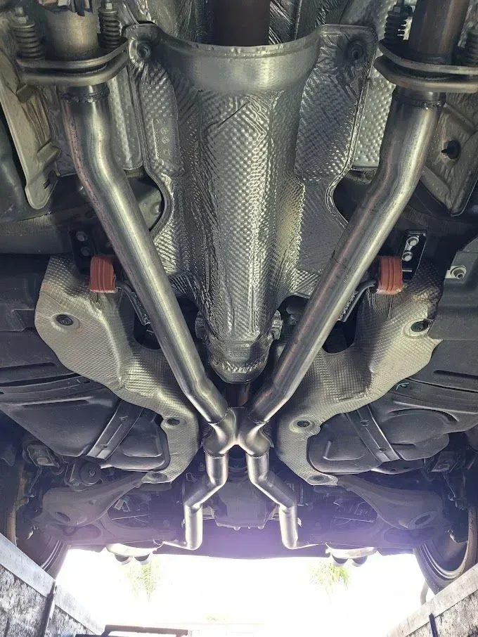A close up of the underside of a car with exhaust pipes | Ed Hanson's Muffler Service