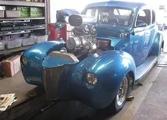 A blue car with a big engine is parked in a garage | Ed Hanson's Muffler Service