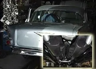 A man is driving a silver car in a garage | Ed Hanson's Muffler Service