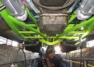 A man is working on the underside of a car | Ed Hanson's Muffler Service