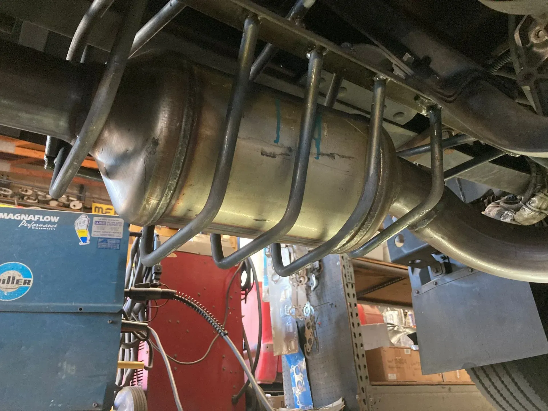 A stainless steel exhaust pipe is attached to the underside of a vehicle | Ed Hanson's Muffler Service