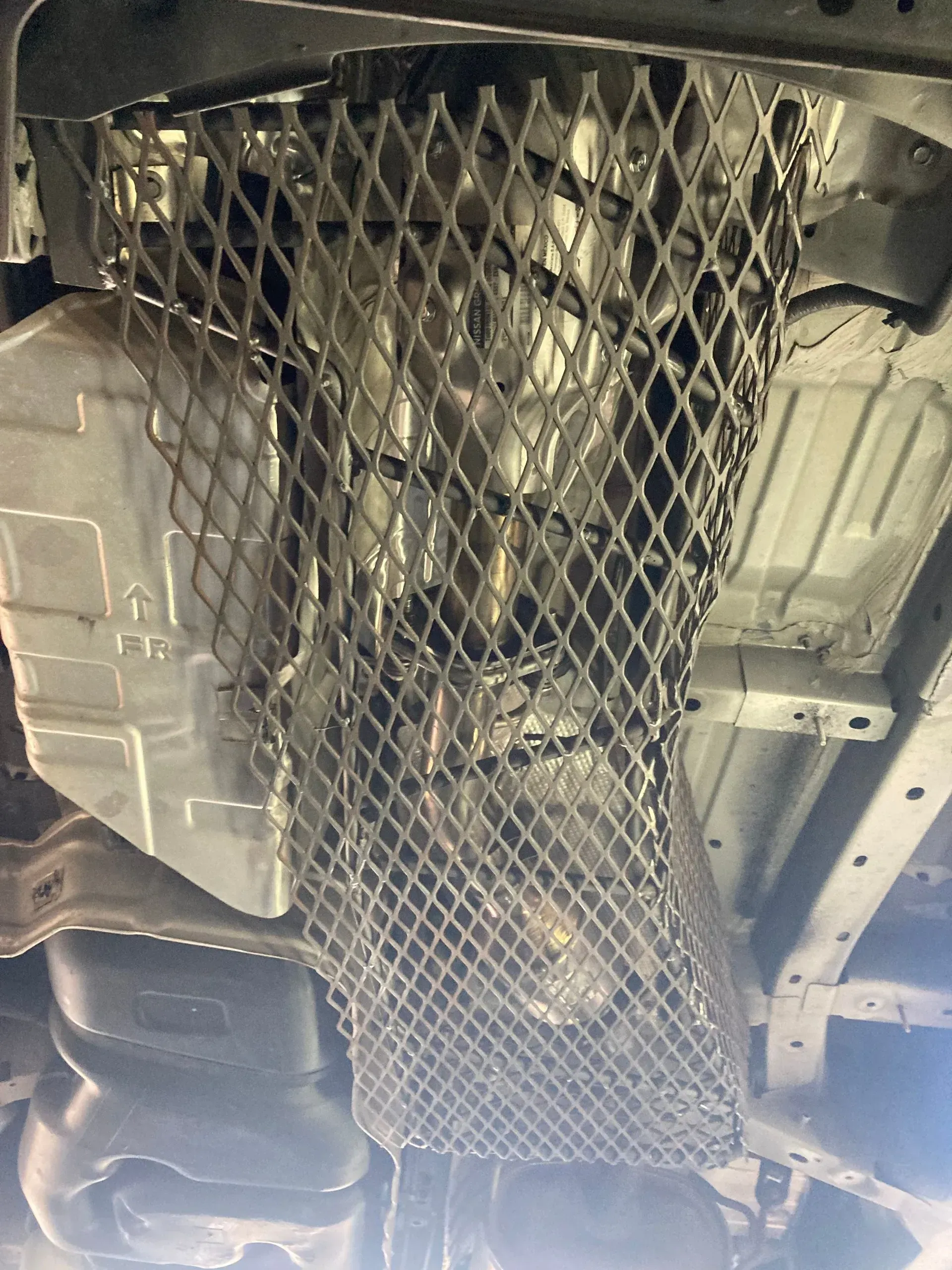The underside of a car with a mesh covering the engine | Ed Hanson's Muffler Service