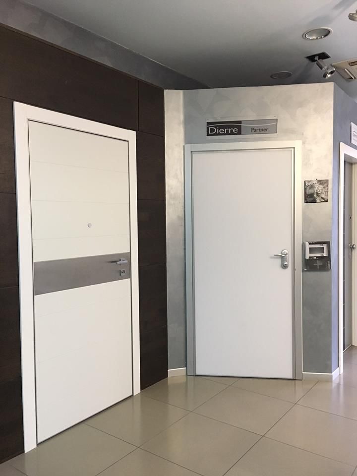 Una porta d'ingresso in legno scuro con un pannello argentato, uno zerbino, pareti neutre e un tavolo decorativo.