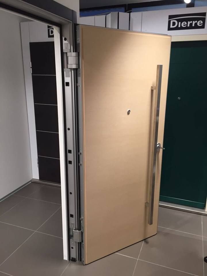 Una porta d'ingresso in legno scuro con un pannello argentato, uno zerbino, pareti neutre e un tavolo decorativo.