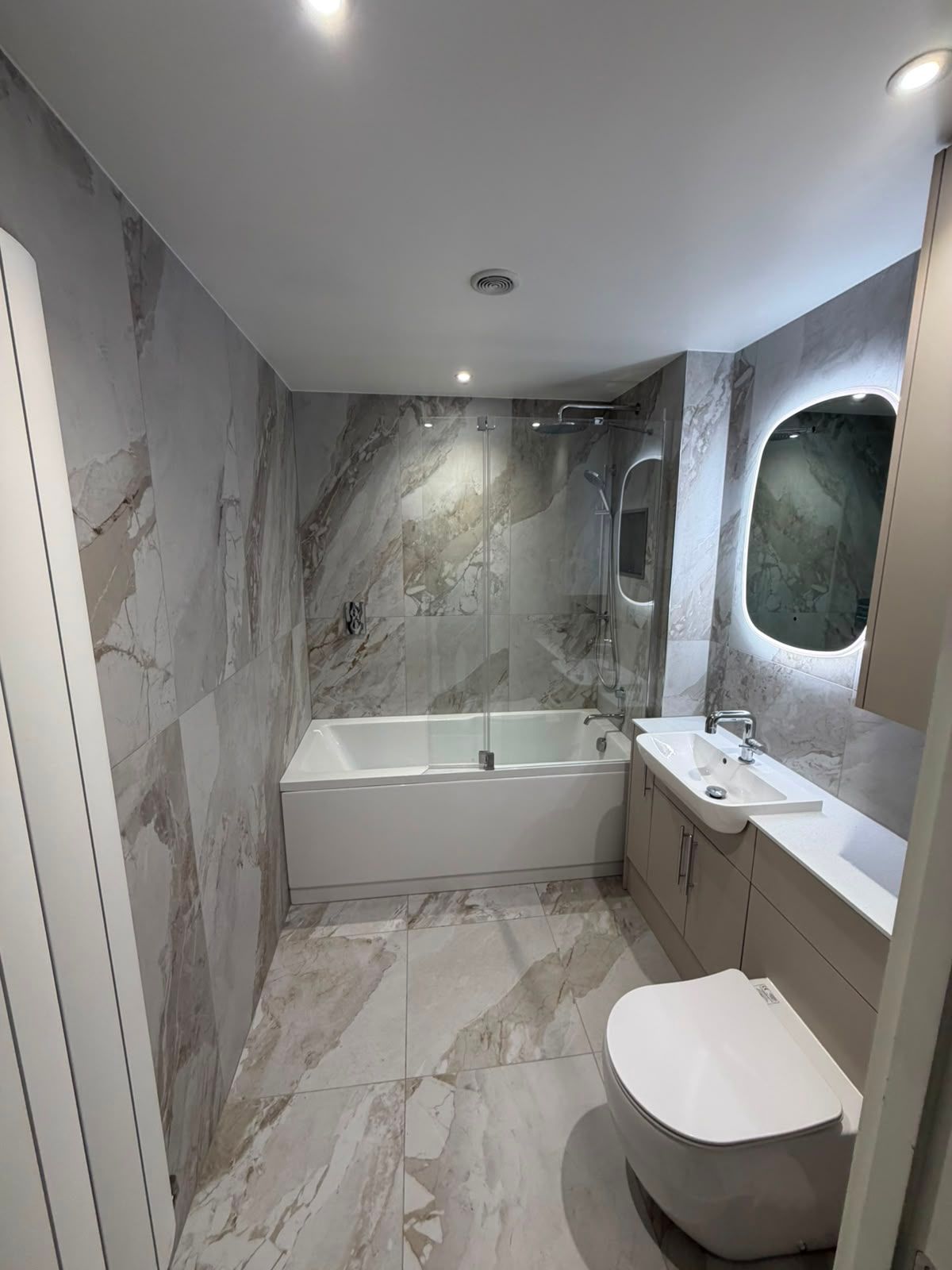 Bathroom renovation by My Life Interiors with fitted vanity storage, large format stone effect tiles and modern shower over bath