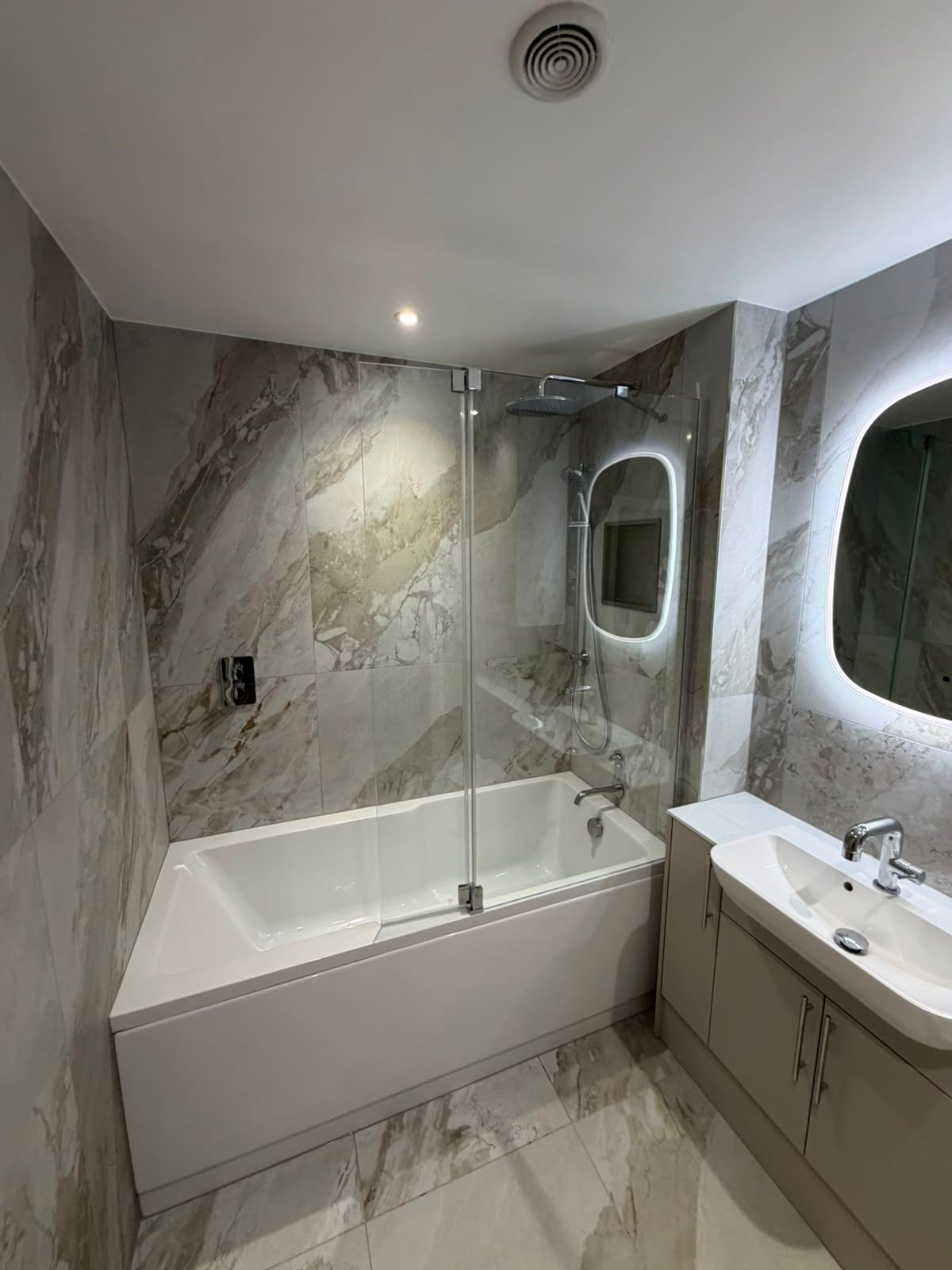 Bathroom renovation by My Life Interiors with stone effect tiles, fitted vanity storage and modern shower over bath